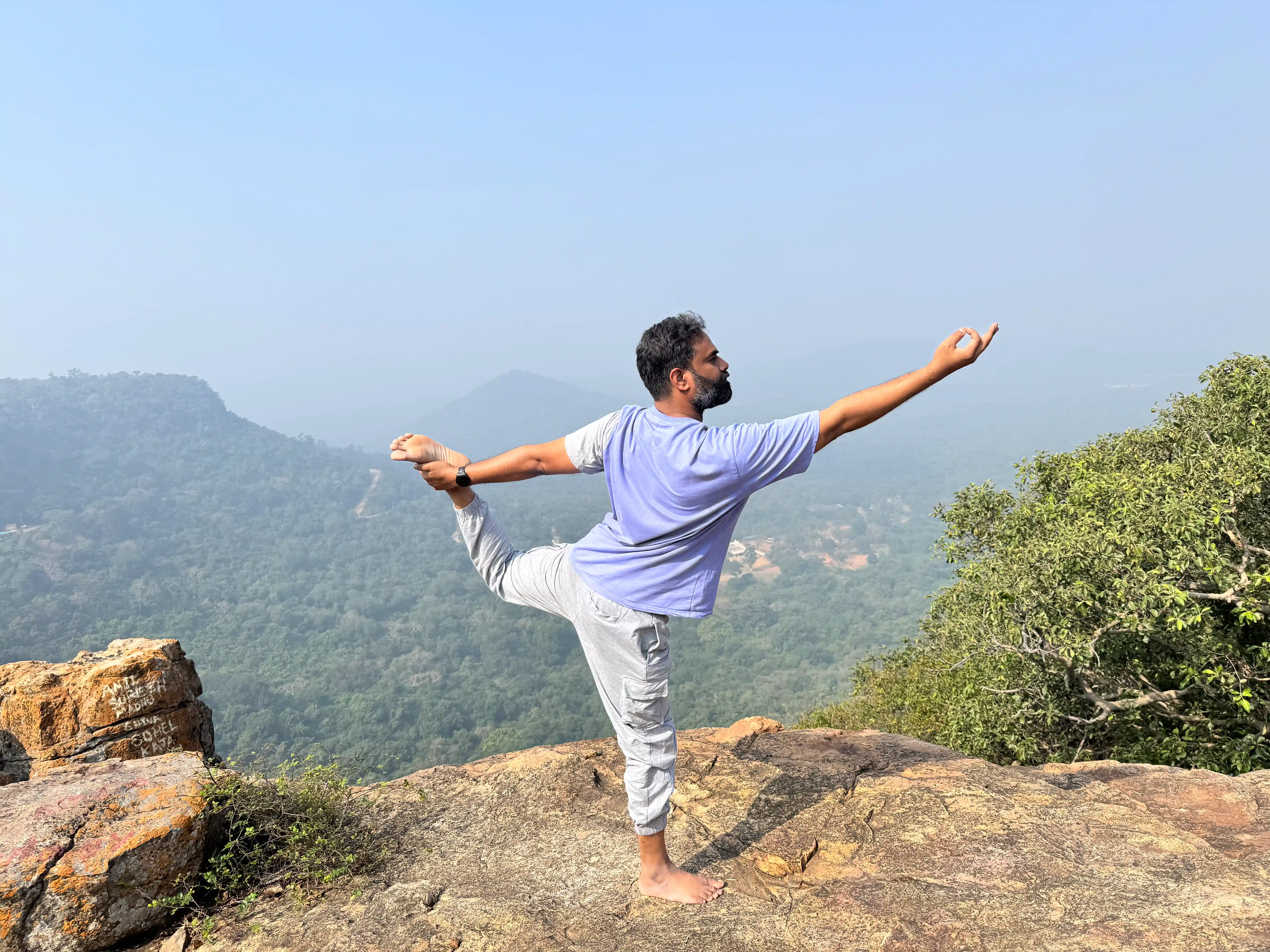 Naveen K. Kolli in Natarajasana on a mountain cliff